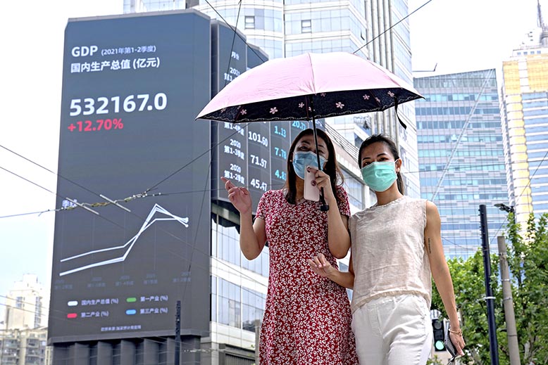 Kvinnor i Shanghai framför skylt med Kinas bnp. Foto: AP/TT