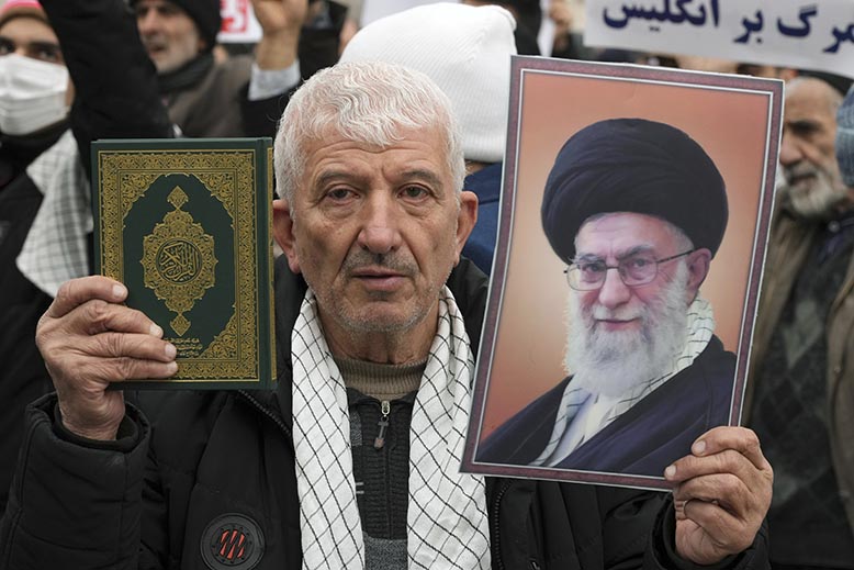 En man håller en koran och ett porträtt av Irans despotiske ledare ayatolla Ali Khamenei vid en protest mot Sverige. Foto: AP/TT