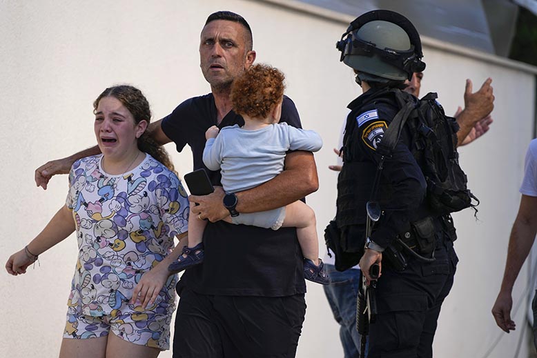 Polis evakuerar familj i Ashkelon under beskjutning från Gaza. Foto: AP/TT